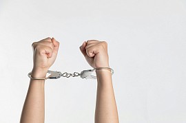 A person's wrists are handcuffed together