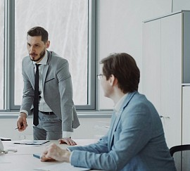 A legal professional stands up at a table while talking to a client.